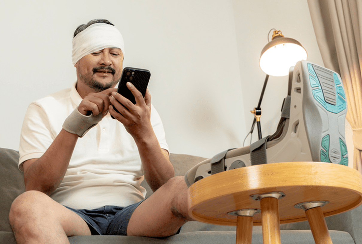 Injured man texting with head bandage